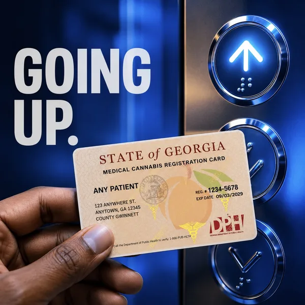 Going up: a hand holding a Georgia medical cannabis card by an elevator button